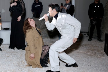 a man singing into a microphone while a woman watches