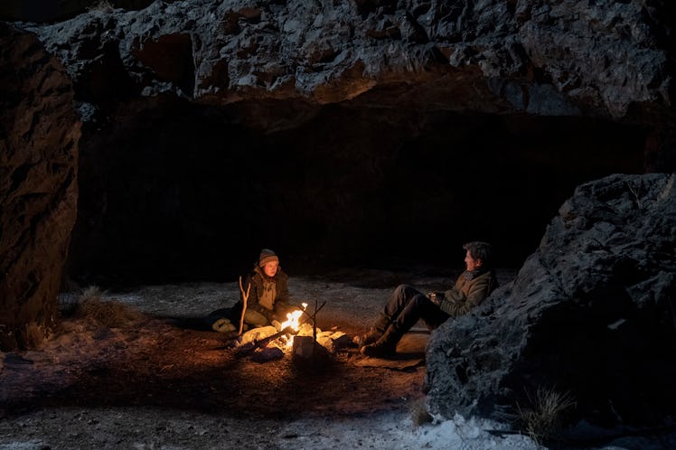Ellie (Bella Ramsey) and Joel (Pedro Pascal) sit next to a campfire in The Last of Us Episode 6