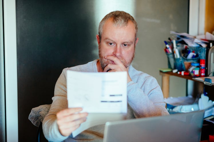 Man sitting at desk staring at piece of financial paperwork
