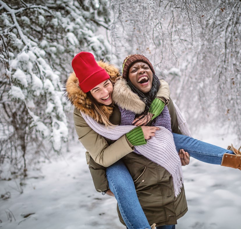 Two young friends piggyback riding in the snow during the February 2023 full Snow Moon, which has a ...