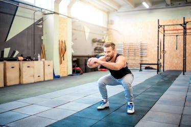 A man doing squats in a gym.