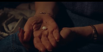 Woman's hands holding a round white pill