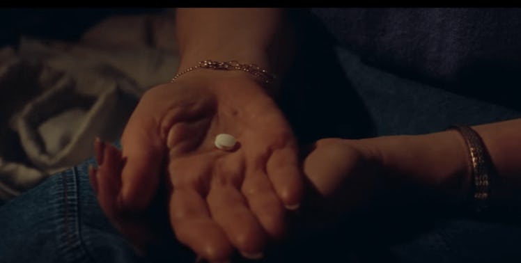 Woman's hands holding a round white pill