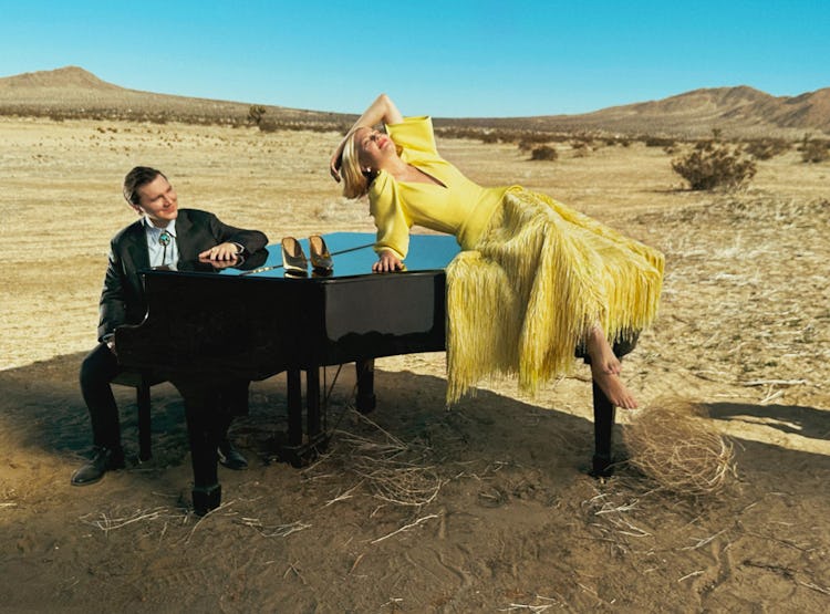 Michelle Williams wears a yellow dress and earrings while lying on a piano.