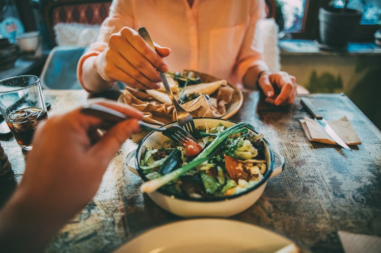 Close up of a man and woman eating salads together.