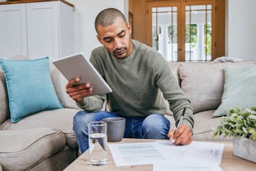 Man sitting on couch doing paperwork for taxes
