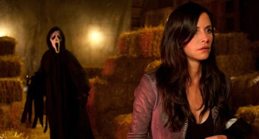Ghostface stands behind Gale Weathers (Courteney Cox) in a barn in Scream 4