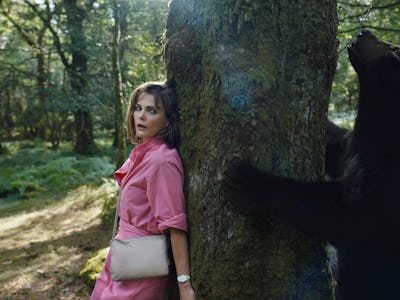 Keri Russell and a bear stand on opposite sides of the same tree in Cocaine Bear