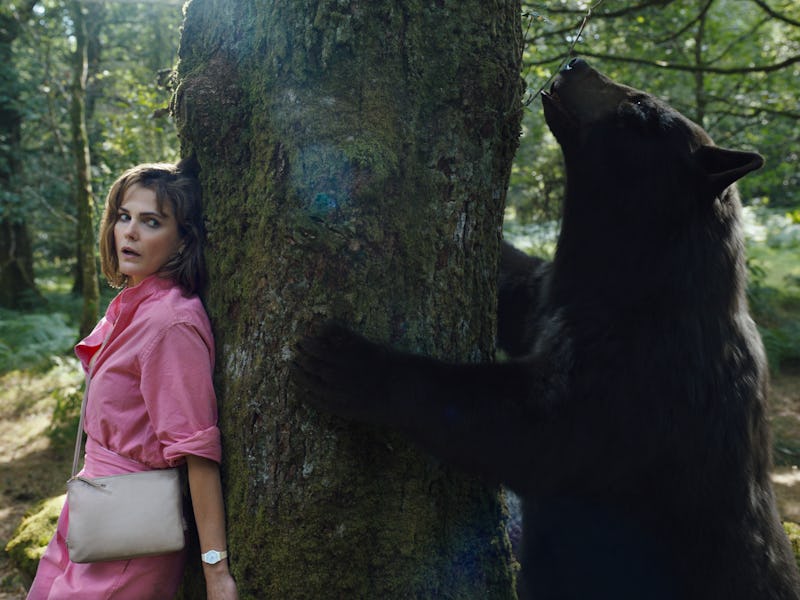 Keri Russell and a bear stand on opposite sides of the same tree in Cocaine Bear