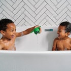 Two kids playing with a toy together in the bathtub.