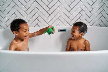 Two kids playing with a toy together in the bathtub.