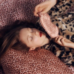 woman with red hair and red lipstick laying in bed with leopard sheets