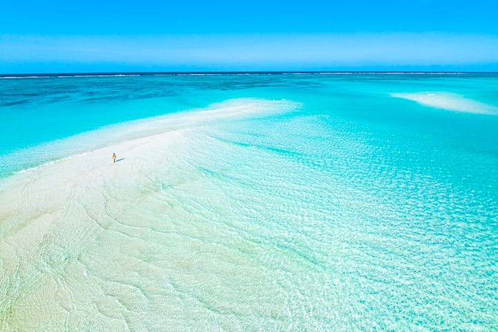 Aerial view of woman walking on sandbank in the middle of the blue ocean during, Nungwi, Zanzibar, T...
