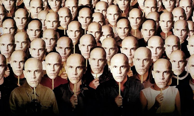 Dozens of people hold John Malkovich masks in front of their faces on the poster for Being John Malk...