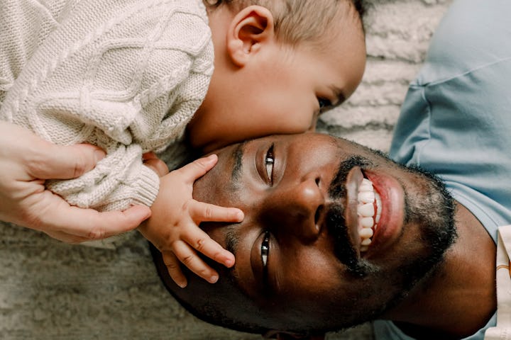 A dad and his baby lying on a beige rug