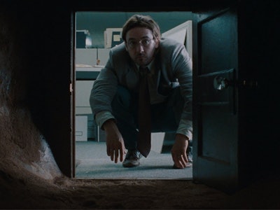 John Cusack crouches in front of a small tunnel in Being John Malkovich