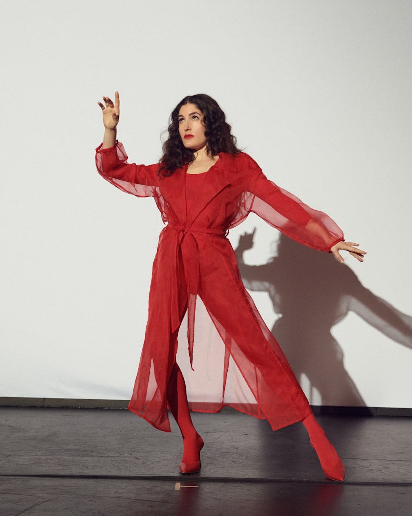 Kate Berlant wears Herno coat, stylist's own bodysuit, Manolo Blahnik shoes, Falke tights