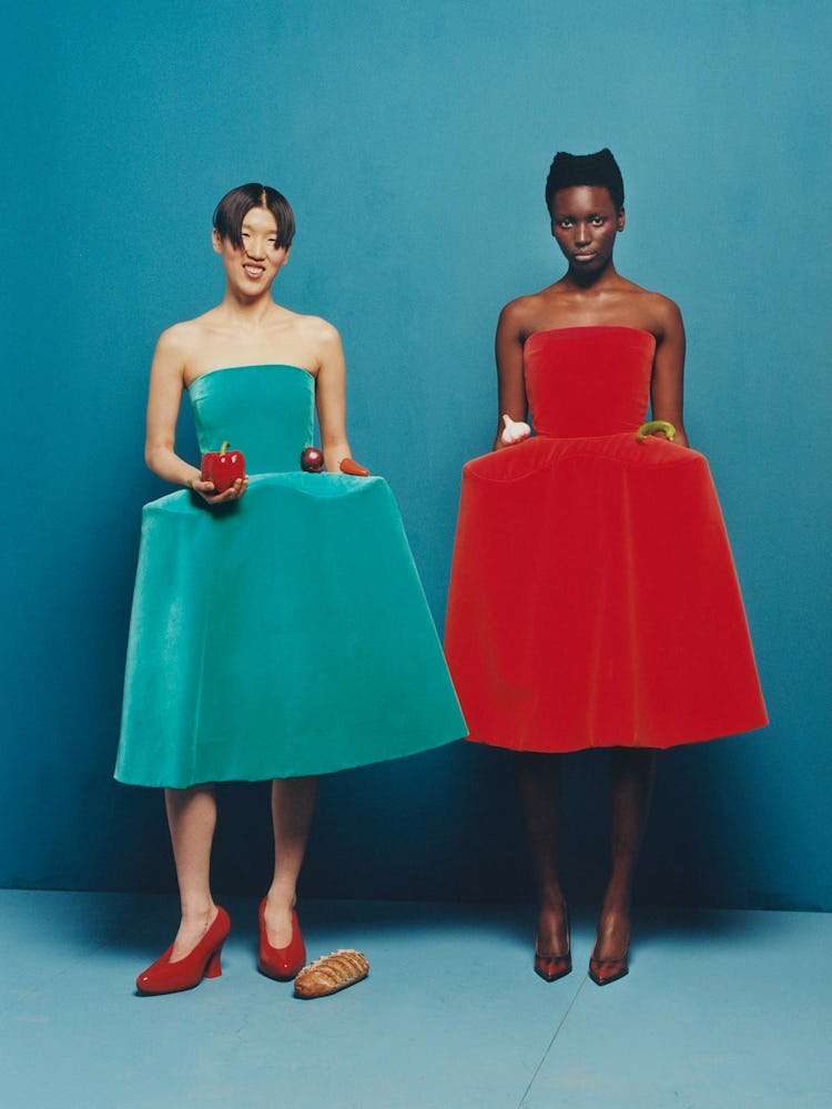Models wearing green & red dresses with red shoes