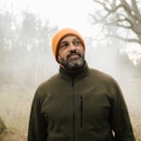Smiling man in foggy woods orange beanie and olive-colored jacket