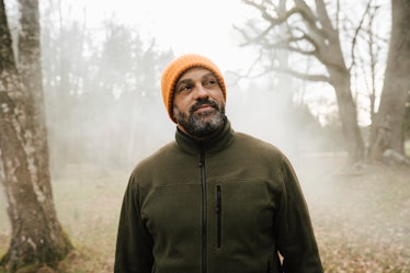 Smiling man in foggy woods orange beanie and olive-colored jacket