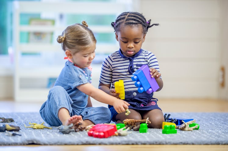 Two toddlers engaging in parallel play with blocks and other toys.