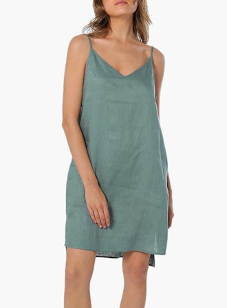 This 100% linen slip dress features adjustable spaghetti straps and a dropped split hem