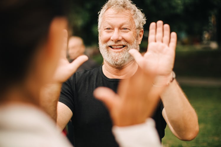 A man holds up his hands to high-five another man.