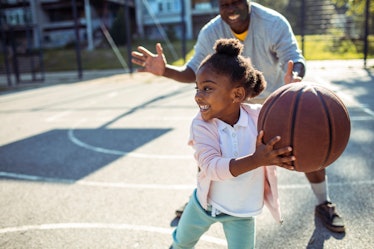 一个女孩和她爸爸在打篮球
