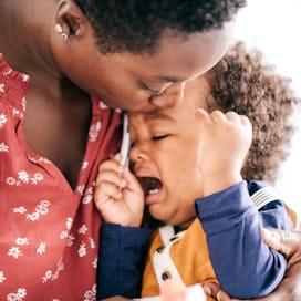 A child throwing a tantrum being held by their mother.