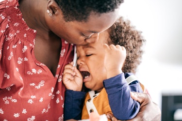 A child throwing a tantrum being held by their mother.