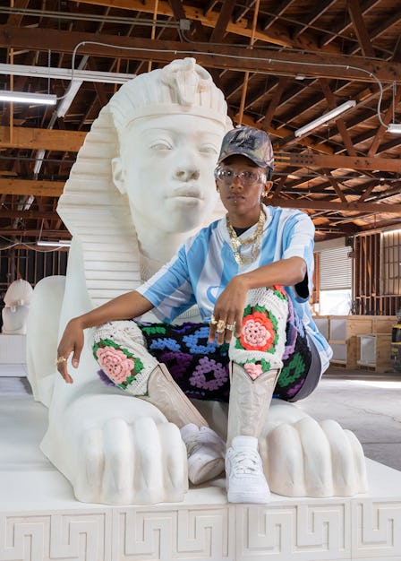 The artist Lauren Halsey, seated on one of the four sphinxes that are part of her latest work, 'the ...