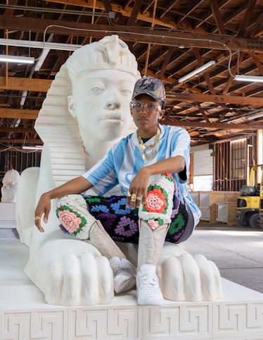 The artist Lauren Halsey, seated on one of the four sphinxes that are part of her latest work, 'the ...