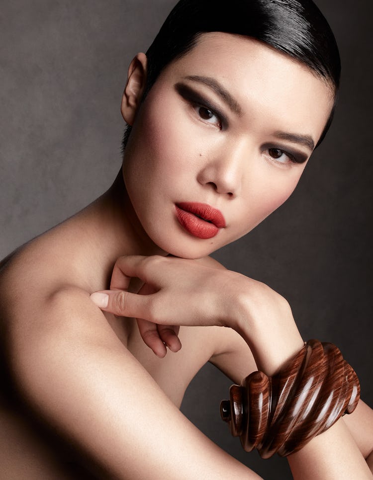 Model Kayako Higuchi wears a brown bracelet and red lipstick.