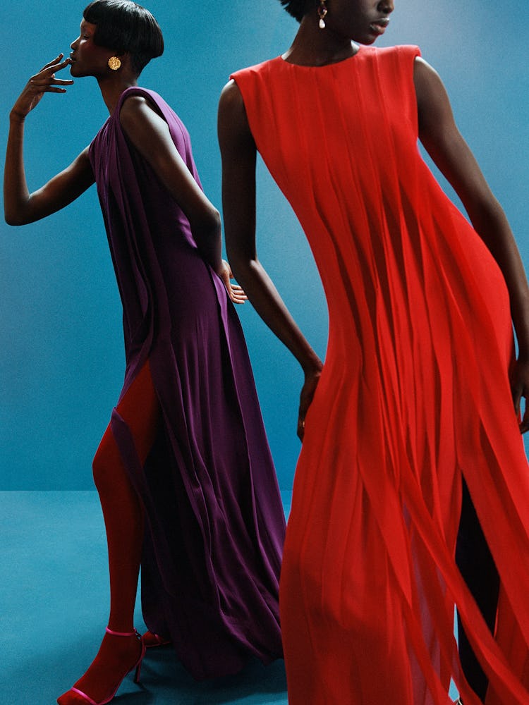 Models Nhial wears a purple dress, red panty hose and gold earrings. Model Ruea wears a red dress an...