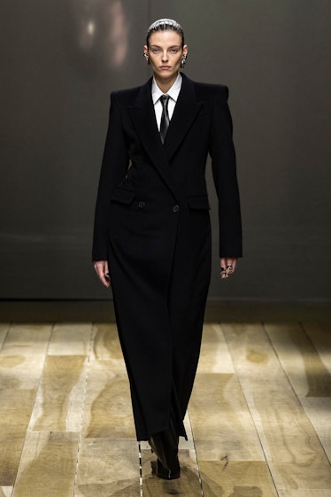 a model wearing a mens-suiting inspired look with a necktie walks the runway