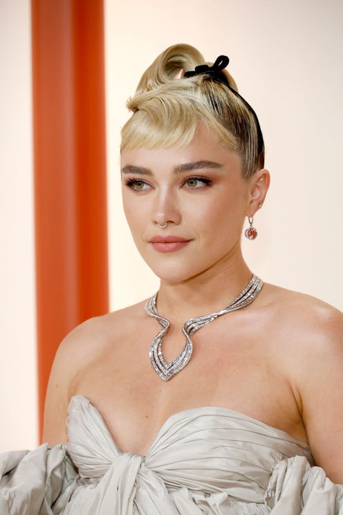 Florence Pugh's 2023 Oscars hairdo features a structural updo that uses her ponytail as micro bangs....