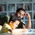 A child struggles to do his homework as his dad helps.