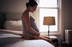 一个孕妇坐在床上，捂着肚子。