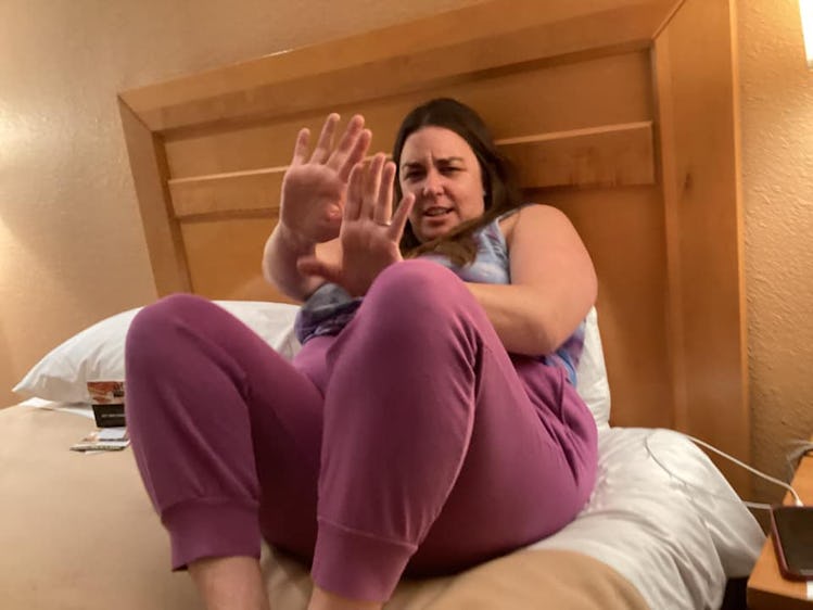 photo of a mom in bed raising her hands as if to say, "no pictures!"