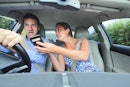 女人给开车的男人看手机