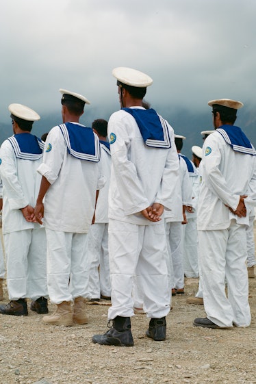 the backs of sailors wearing white uniforms with blue flaps