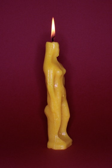 a picture of a yellow candle in the shape of a woman