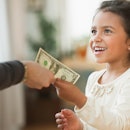 A parent handing a child a dollar as allowance.
