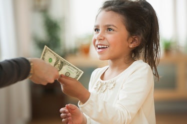 A parent handing a child a dollar as allowance.