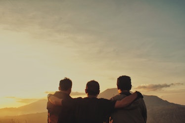 Three adult friends on a mountaintop looking out across the sky