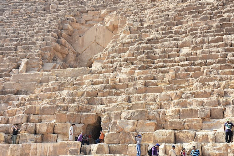 Photo of the north face of the Great Pyramid, ascending rows of limestone blocks with a chevron-shap...