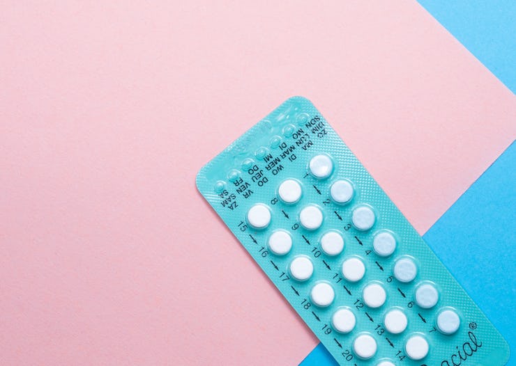 A packet of while pills on a blue and pink background.