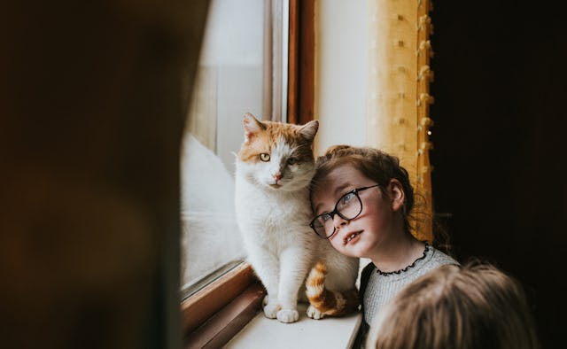 A little girl cuddles the family cat.