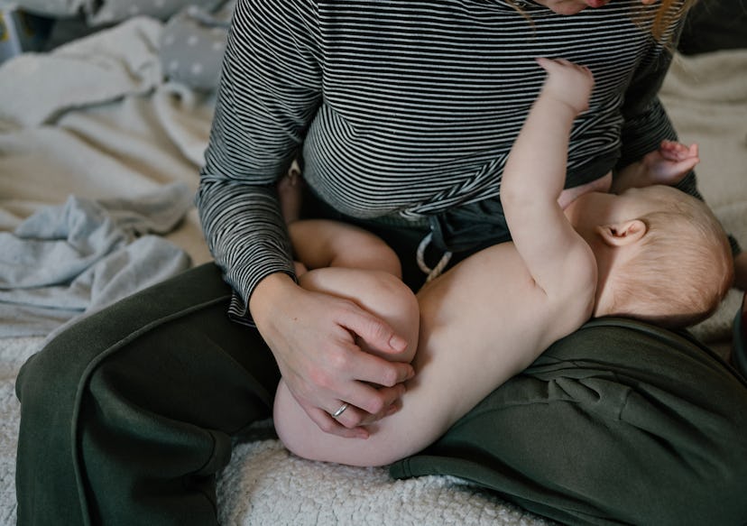 Person holds a baby on their lap while breastfeeding