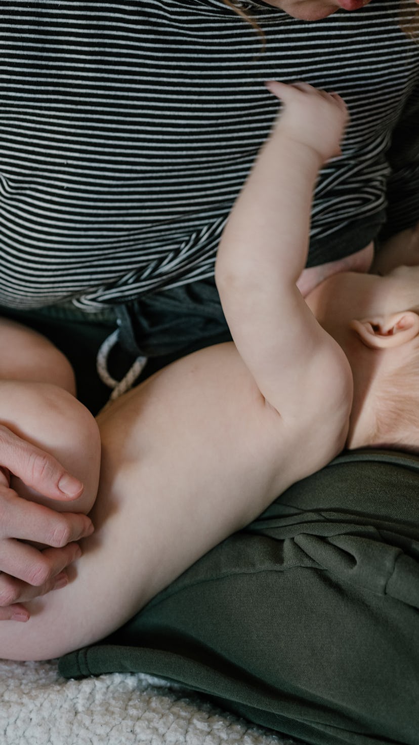 Person holds a baby on their lap while breastfeeding